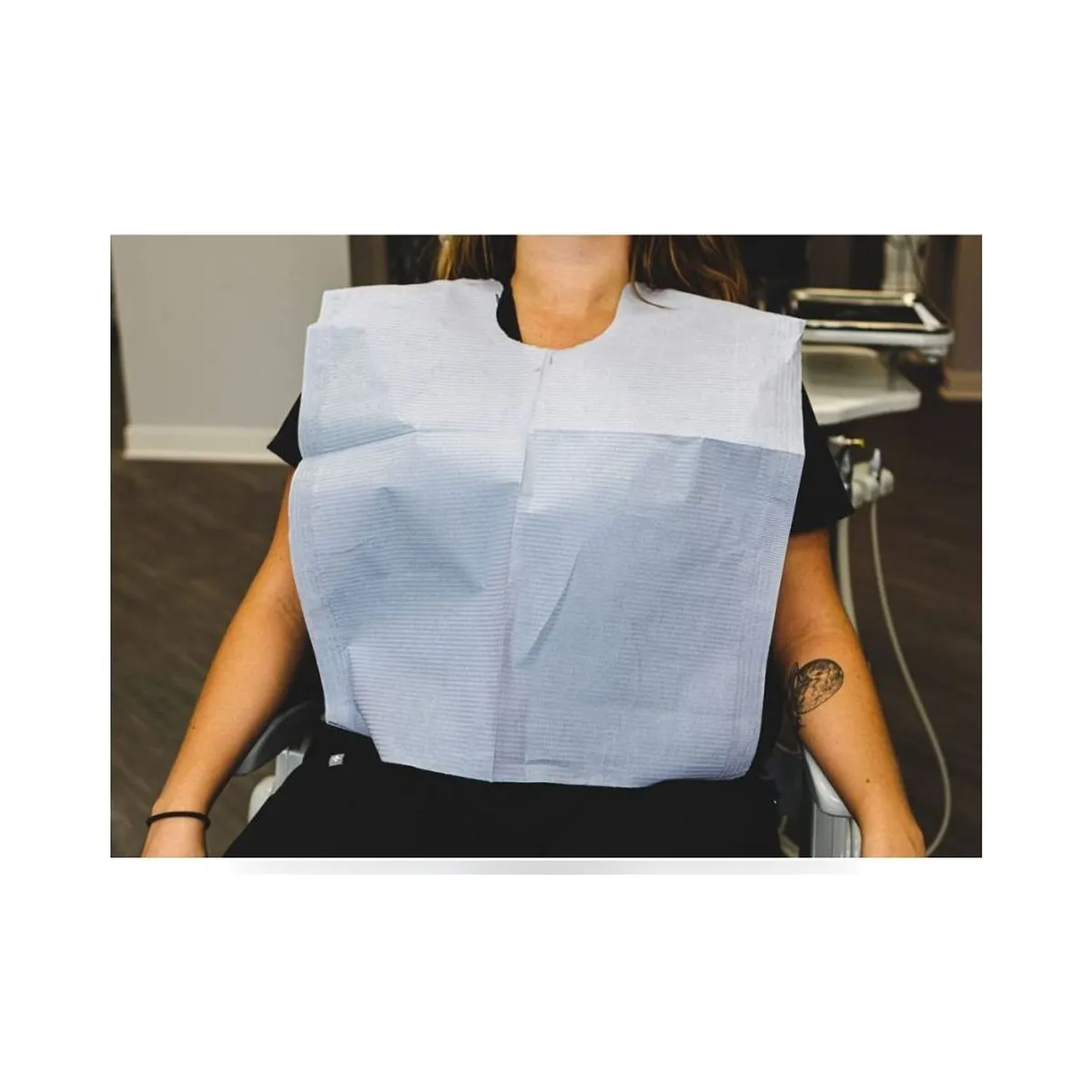 Folded UMD 46 x 56 cm dental bibs with perforated cut neck and adhesive strip.